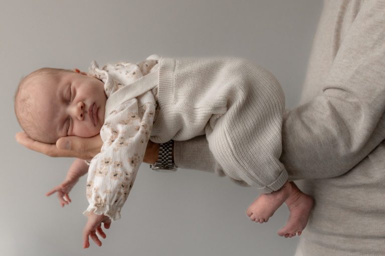 Baby wordt liefdevol vastgehouden op de buik door een mannenarm .