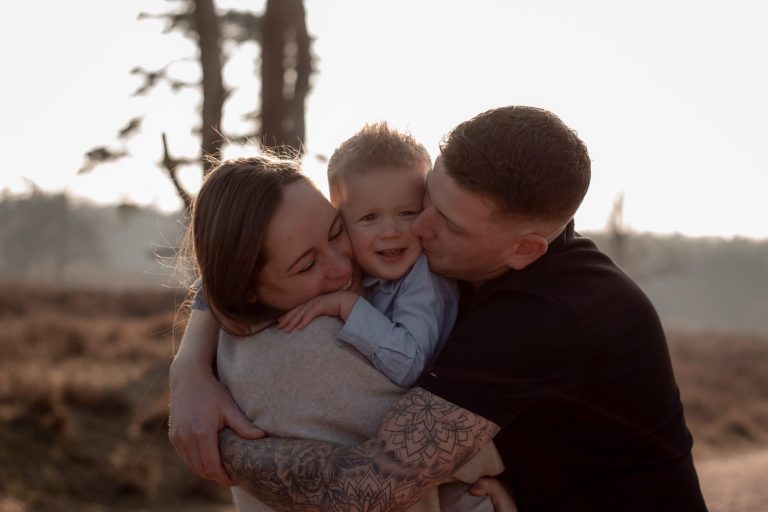 Een gelukkige familie met een kind dat wordt omhelst door ouders in de natuur.