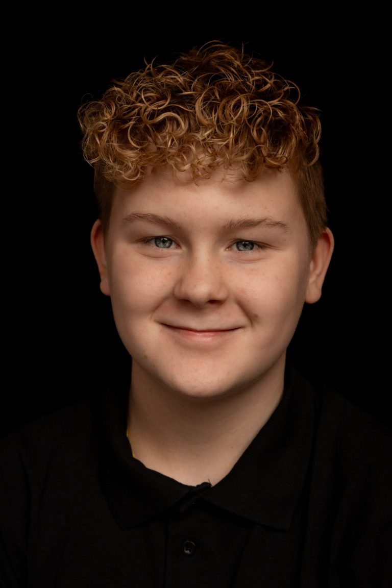 Jongeman met krullend, blond haar en een glimlach, gekleed in een zwart T-shirt.