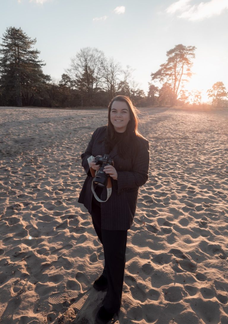 Vrouw houdt tijdschrift vast bij een Amsterdamse gracht, bomen en gebouwen op de achtergrond.