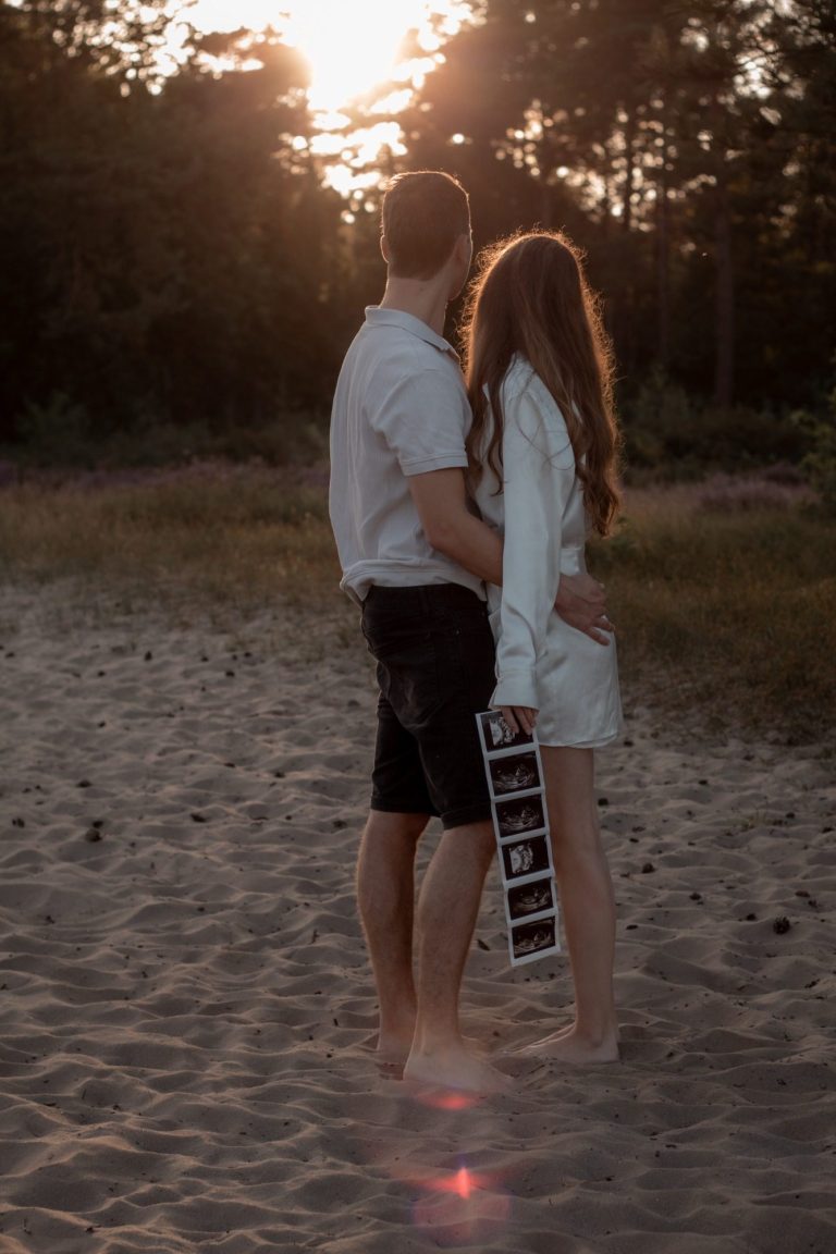 Twee mensen omhelzen elkaar op het strand bij zonsondergang.