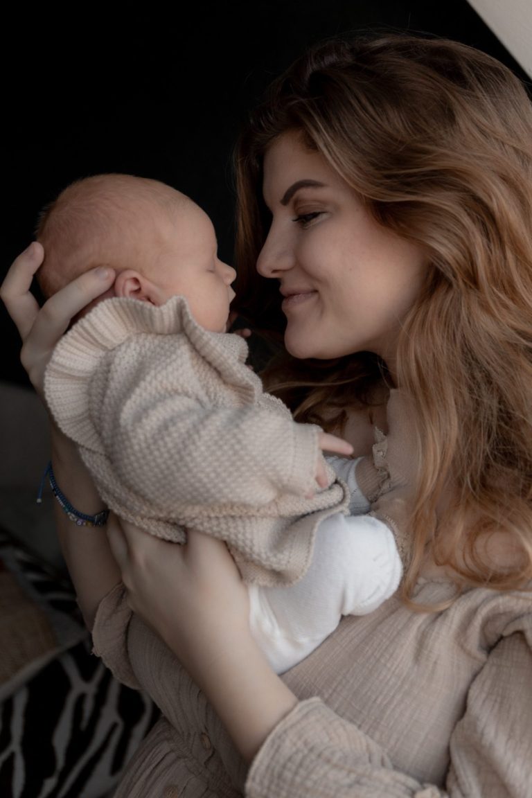 Moeder kust haar pasgeboren baby terwijl ze haar voorzichtig vasthoudt.