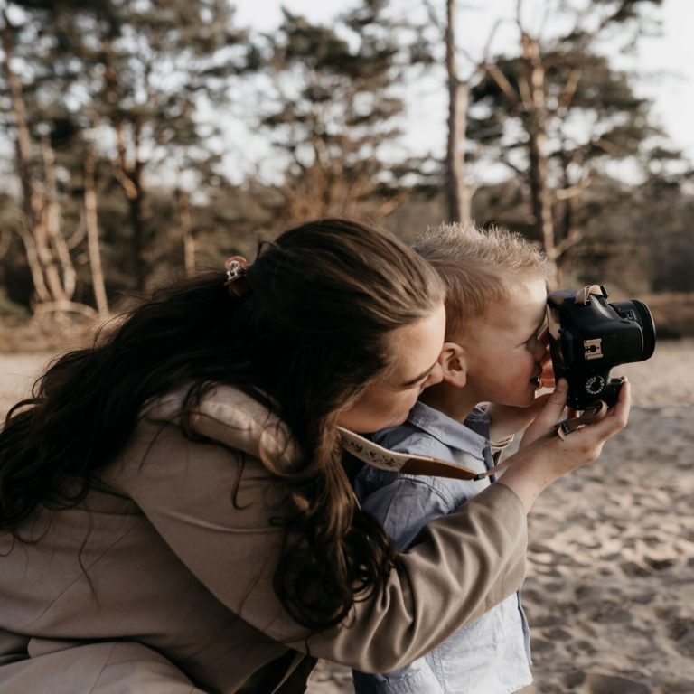 Een fotograaf laat een kind een foto maken op het strand