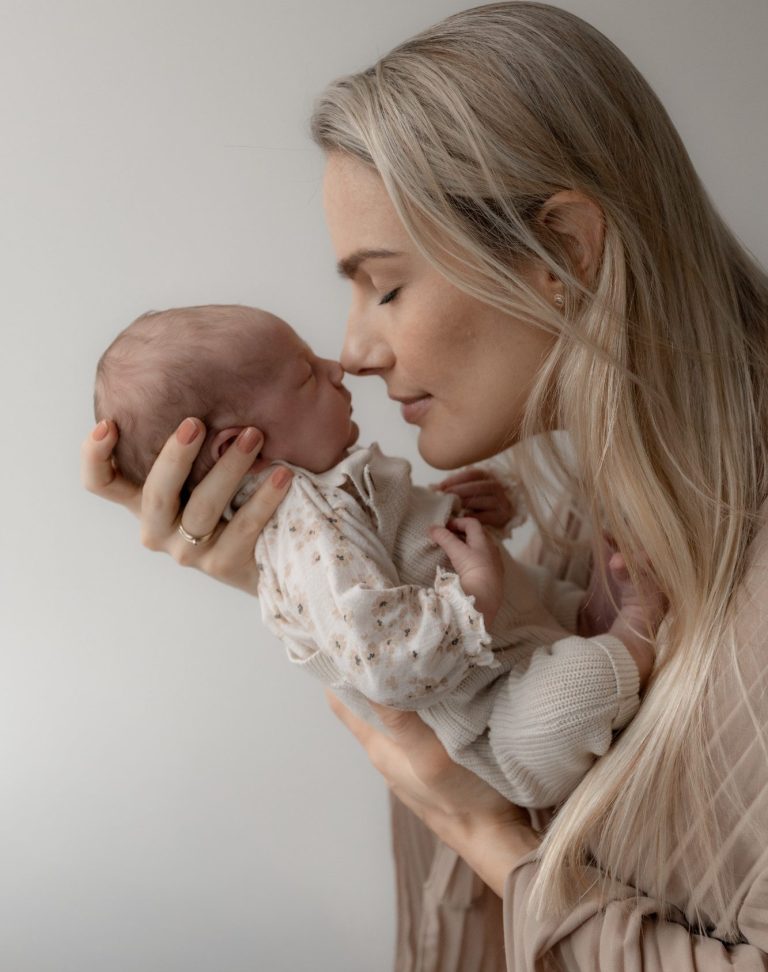 Moeder en pasgeboren baby delen een intieme aanraking met een liefdevolle blik.