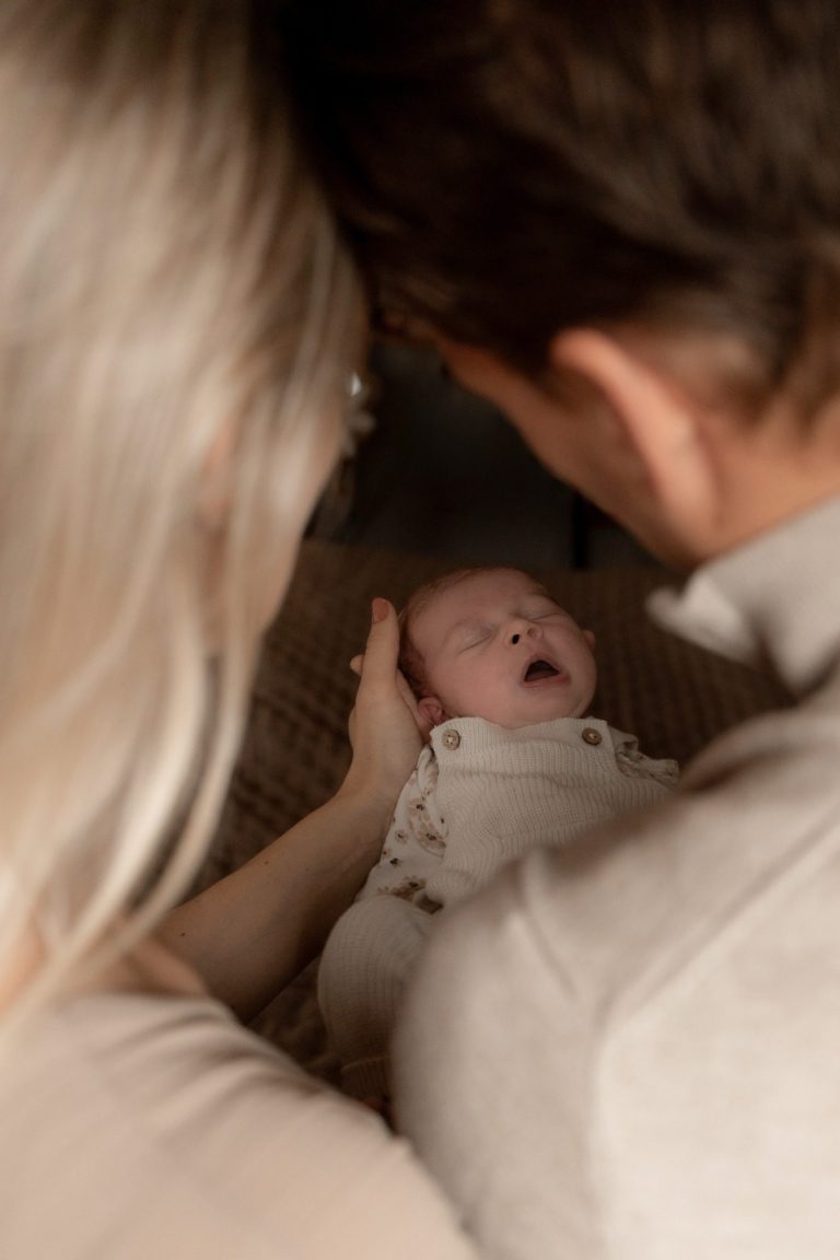 Een baby ligt in de armen van een volwassene, met een blik van verwondering.