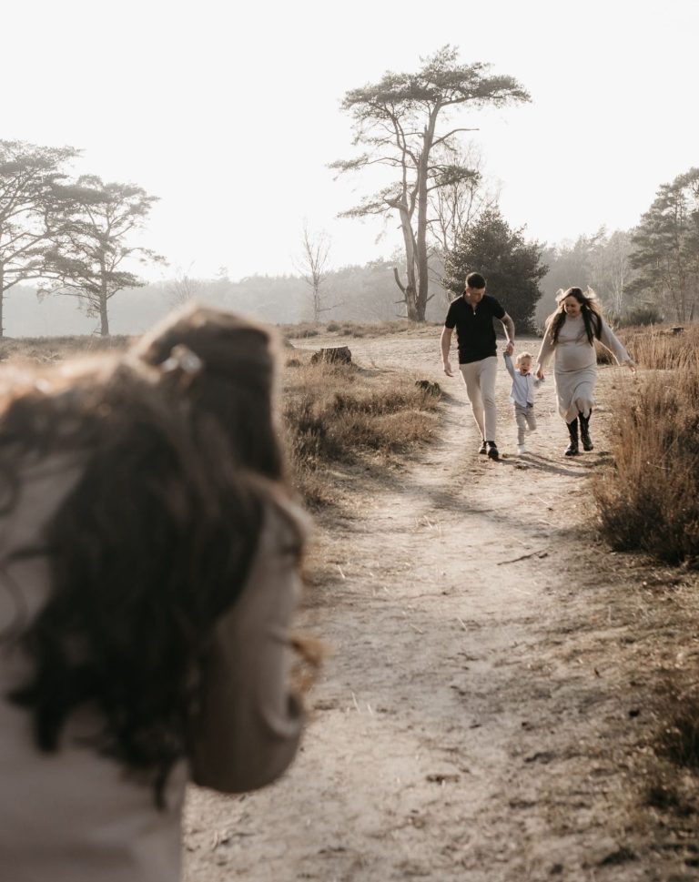 Een gezin wandelt samen over een pad in een bosrijke omgeving.