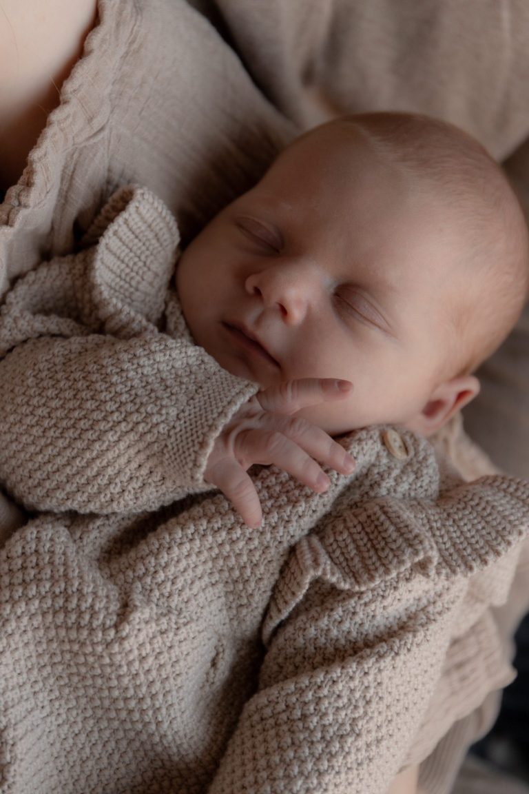 Moeder kijkt liefdevol naar haar baby op een bed.