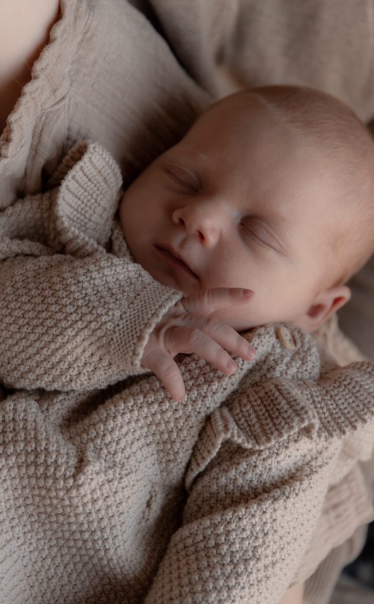 Moeder kust haar zich uitrekkende baby op een zachte ondergrond.