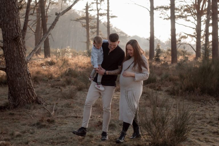 Gezin wandelt samen door een bosrijke omgeving met een zachte zonsondergang.
